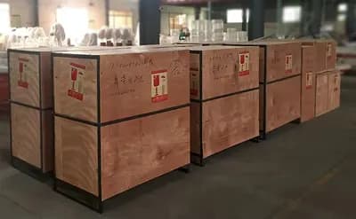 Row of sealed wooden crates with handling marks lined up on the factory floor ready for lottery machine shipment