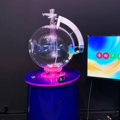 Fast draw lottery machine with pink LED lighting next to a display screen showing drawn winning ball numbers