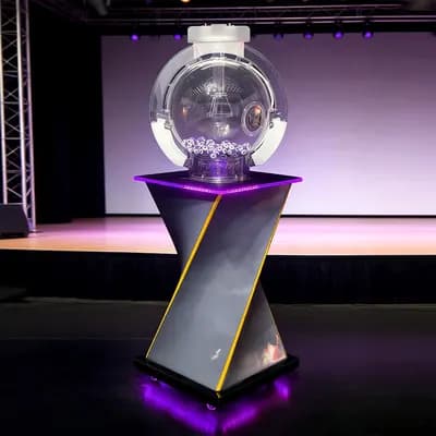 Front view of the MS04 Mark Six lottery machine on a twisted stand with purple LED lighting and numbered balls inside the clear globe