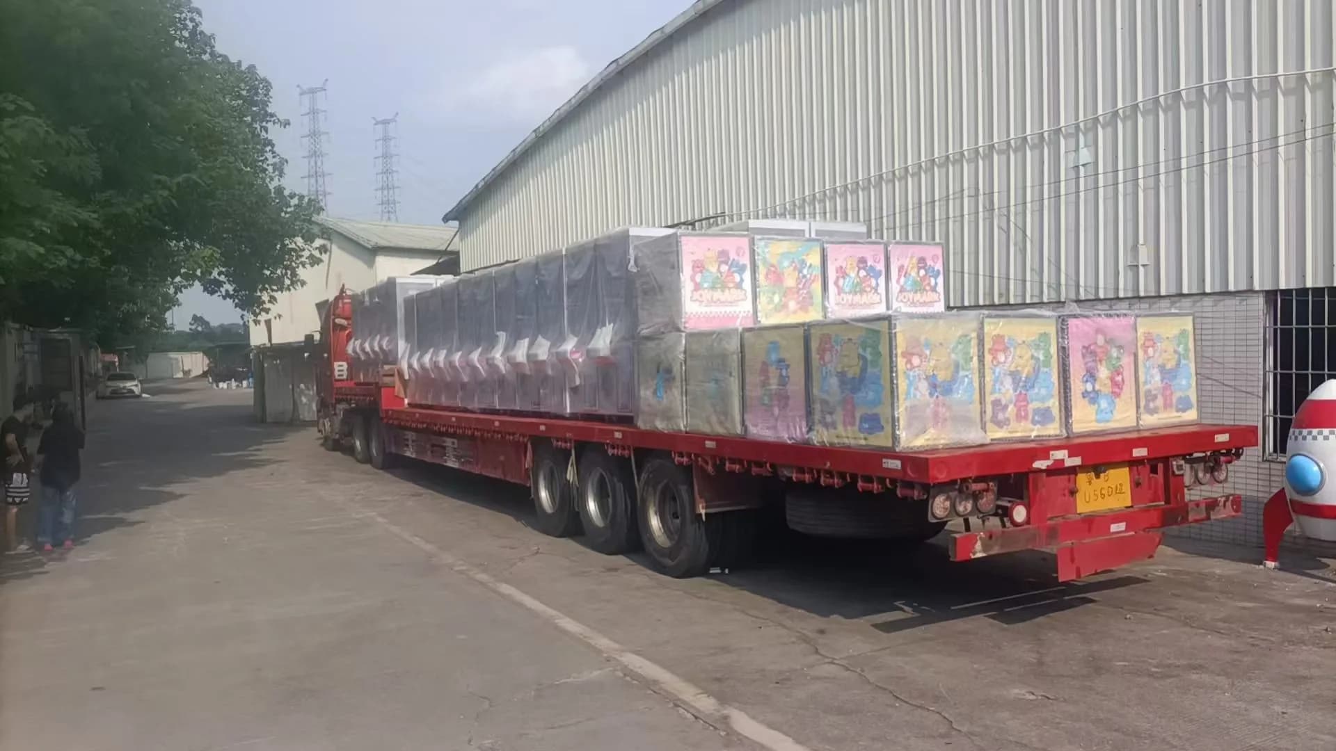 A full flatbed trailer loaded with wrapped arcade machines outside the Jisun factory