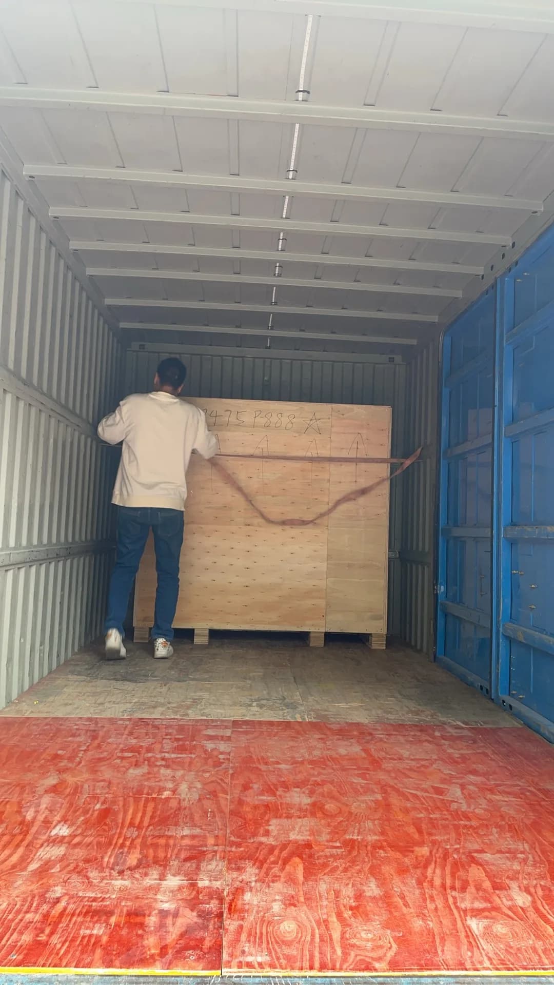 Packing worker positioning a wooden lottery machine crate inside a shipping container